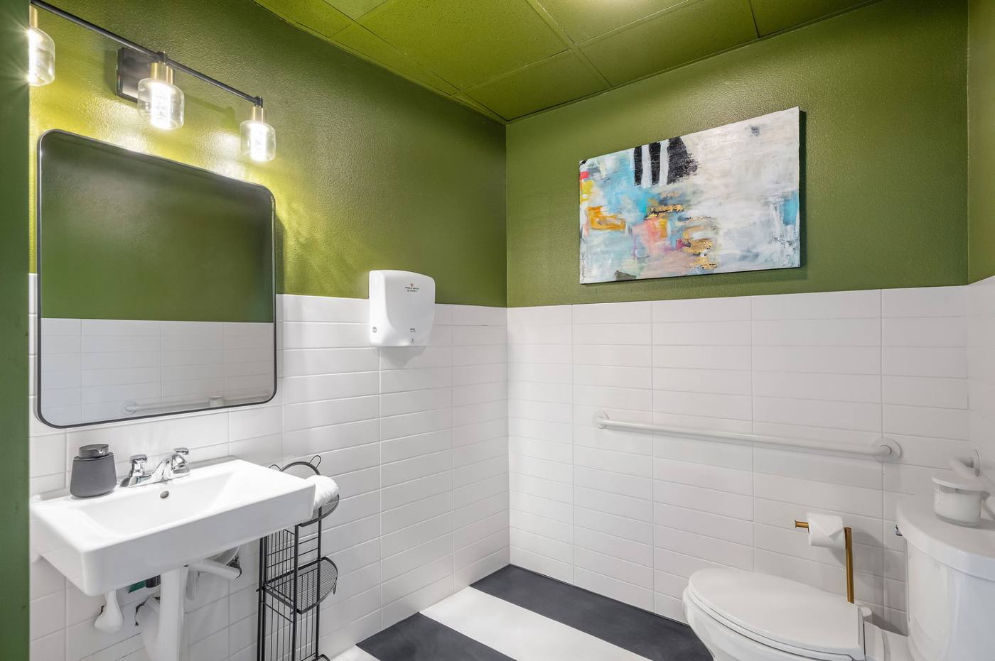 The Clubhouse common bathroom with white tile and green painted walls